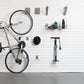 Wall-mounted bike storage system featuring a bike, hooks, basket, and pump for efficient organization.